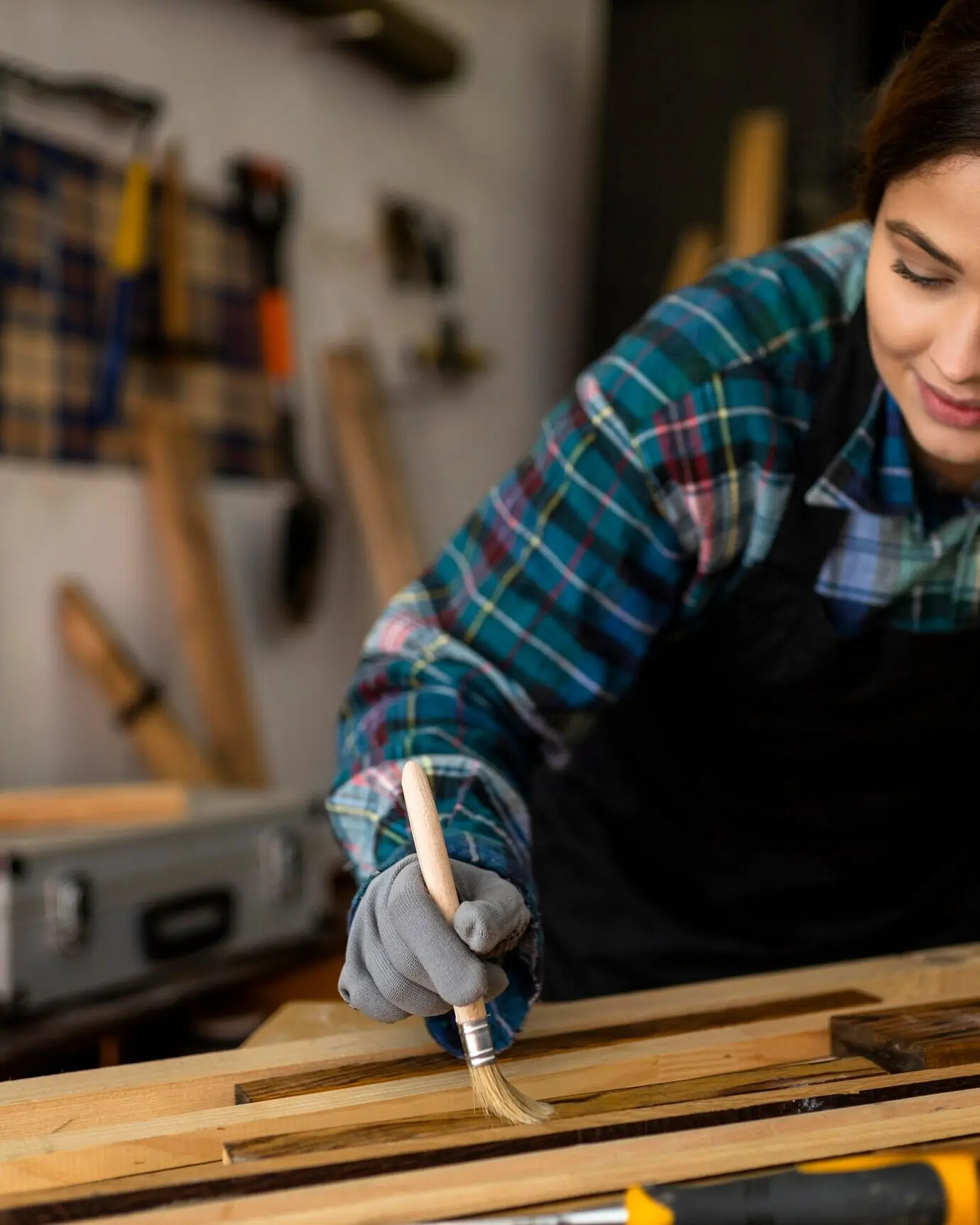 Eine Frau in einer Werkstatt bürstet Staub von Holzplanken.